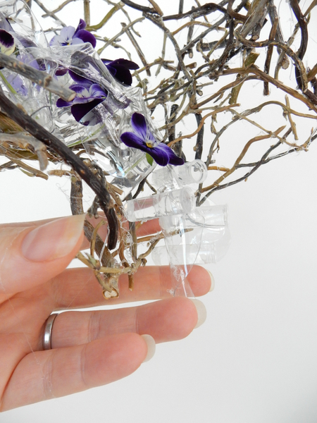 Continue to add plastic shapes and tubes to spill out of the twig vase armature