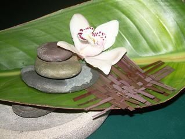 Orchid floating in a birds of paradise leaf