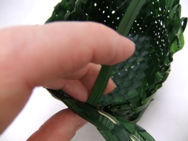 Stitch the first band around the rugged top rim of the basket with grass. Stitch the first band around the rugged top rim of the basket with grass.