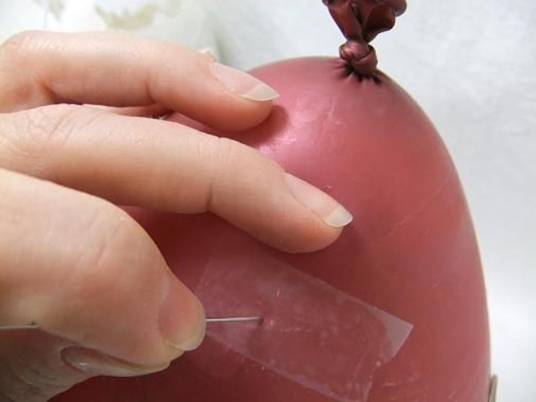 Make a hole in the balloon through the tape with a pin. Make a hole in the balloon through the tape with a pin.