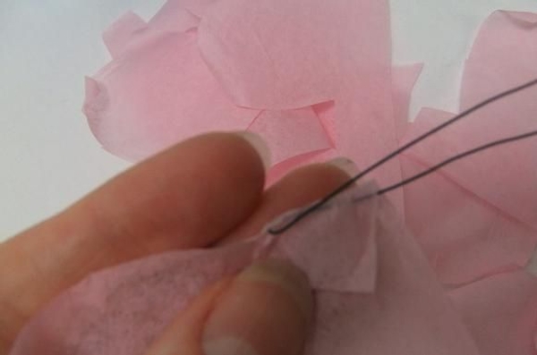 Hook the wire through the tissue paper and start to roll the petals. Hook the wire through the tissue paper and start to roll the petals.