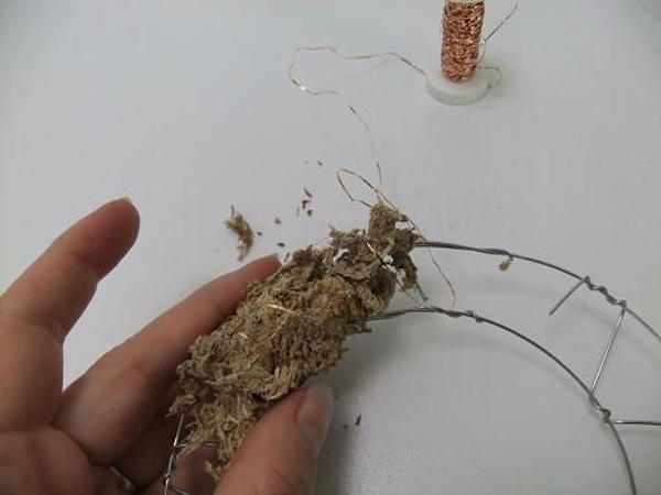 Gather a handful of moss or growth medium and wire it to the frame. Gather a handful of moss or growth medium and wire it to the frame.