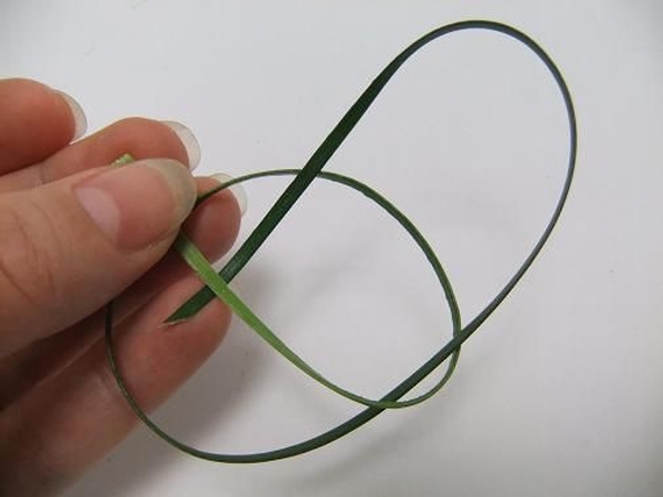 Bend the right leg in and weave it under the middle blade of grass Bend the right leg in and weave it under the middle blade of grass