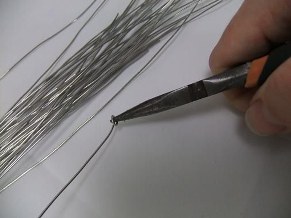 Roll the wire in a tight spiral at one end. Roll the wire in a tight spiral at one end.