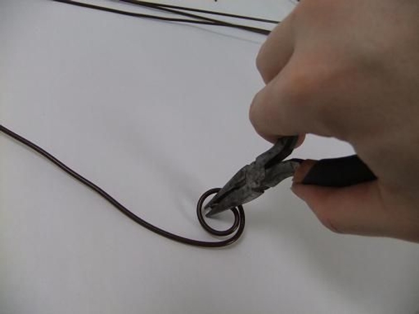 Curl the top of the first wire with pliers. Curl the top of the first wire with pliers.