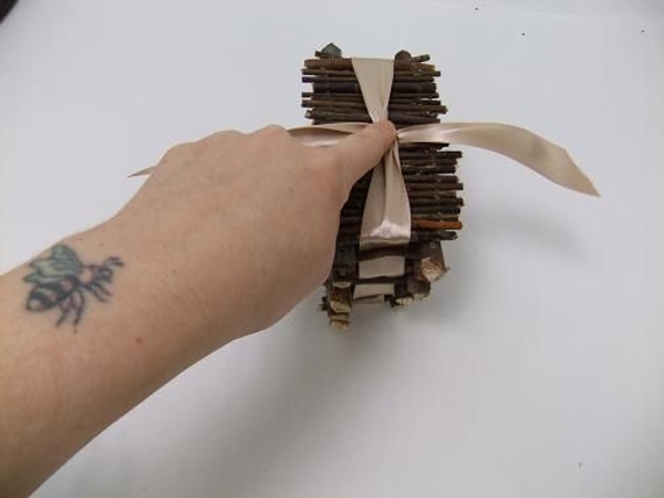 Close the twig flaps and tie the ribbon in a bow to secure Close the twig flaps and tie the ribbon in a bow to secure