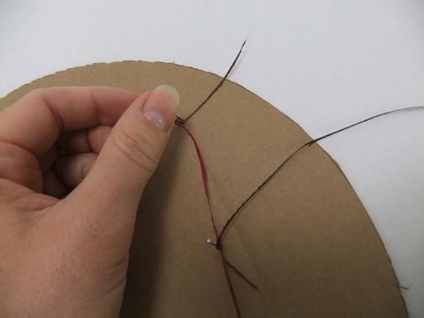 Cut a circle out of cardboard and pin the strands to the cardboard Cut a circle out of cardboard and pin the strands to the cardboard