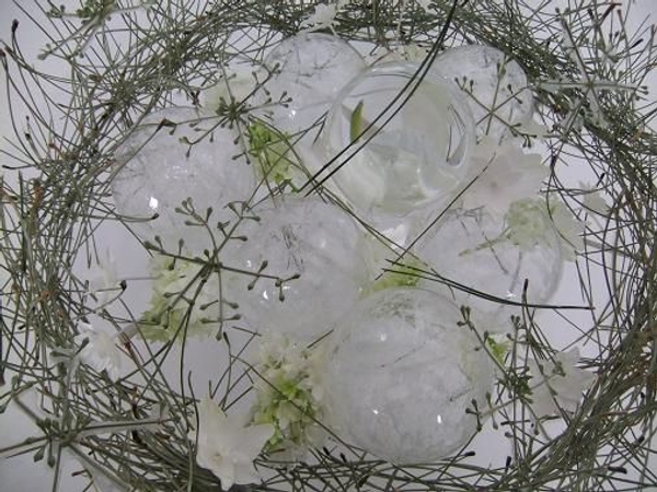 Eucalyptus snow flakes rest on the glass baubles.