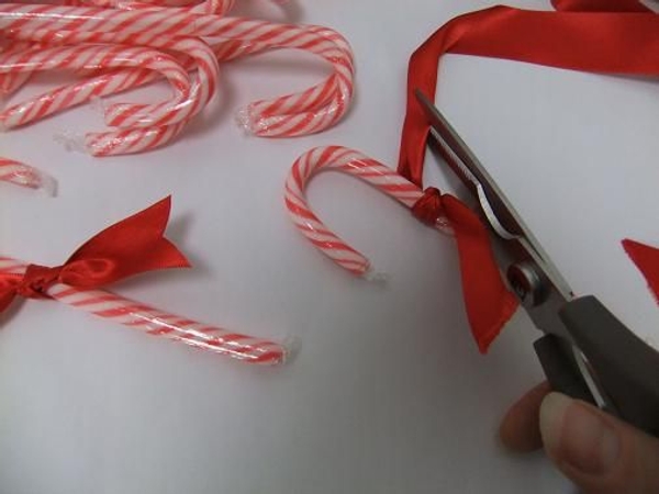 Knot a ribbon around the candy cane and dove-tail the end. Knot a ribbon around the candy cane and dove-tail the end.