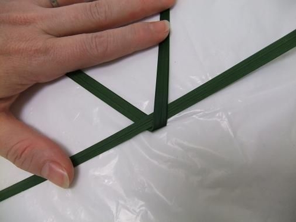 Fold a second blade of grass under and over the first. Fold a second blade of grass under and over the first.