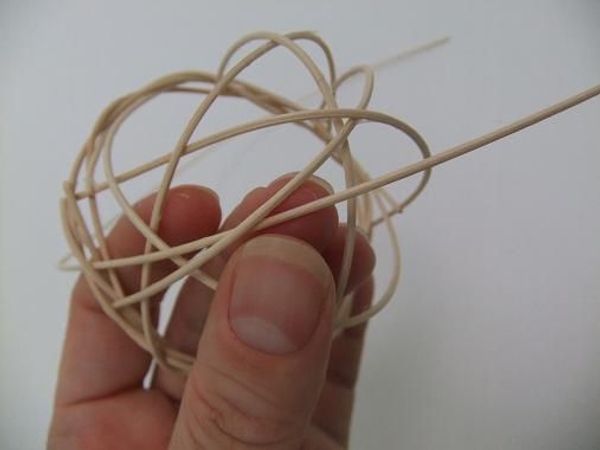 Curve the rattan in and around the bottom of the basket and out at the wreath Curve the rattan in and around the bottom of the basket and out at the wreath