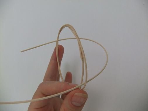 Press a long piece of rattan through the wreath at opposite sides Press a long piece of rattan through the wreath at opposite sides