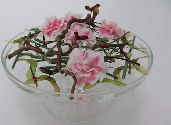 Create a low design with plant material that appears to float on the glass container Create a low design with plant material that appears to float on the glass container