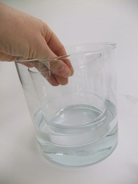 Pour water in the larger vase. Pour water in the larger vase.