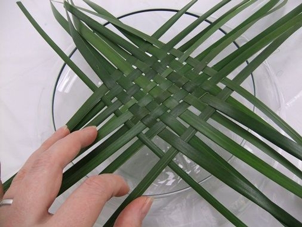 Weave a few strands of foliage in a basic over and under pattern Weave a few strands of foliage in a basic over and under pattern