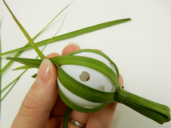Pull the palm leaves so that it follows the rounded shape of the ball.