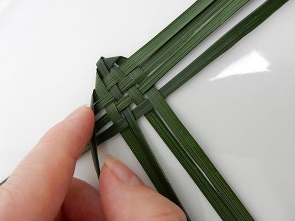 Continue the weaving pattern by folding over the top blade. Continue the weaving pattern by folding over the top blade.