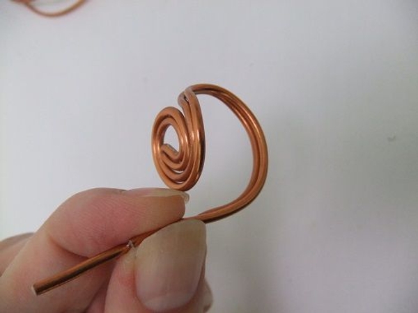 Curve the wire down and around to create the ring part that wraps around the wearers finger Curve the wire down and around to create the ring part that wraps around the wearers finger