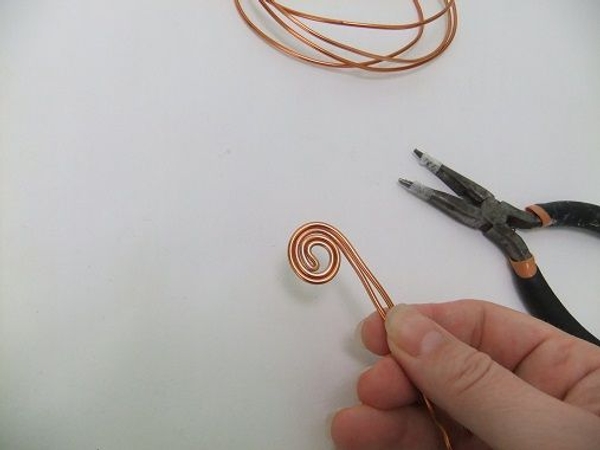Remove the pliers and spiral roll the wire to create the flat top Remove the pliers and spiral roll the wire to create the flat top