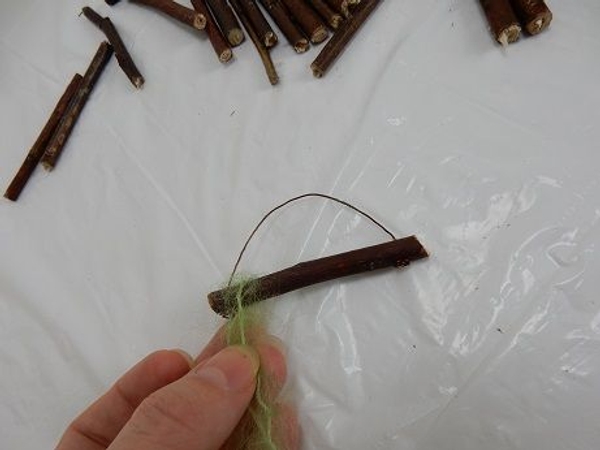 Pull the wool over the twig so that the twig lies in the middle point of the wool strand Pull the wool over the twig so that the twig lies in the middle point of the wool strand
