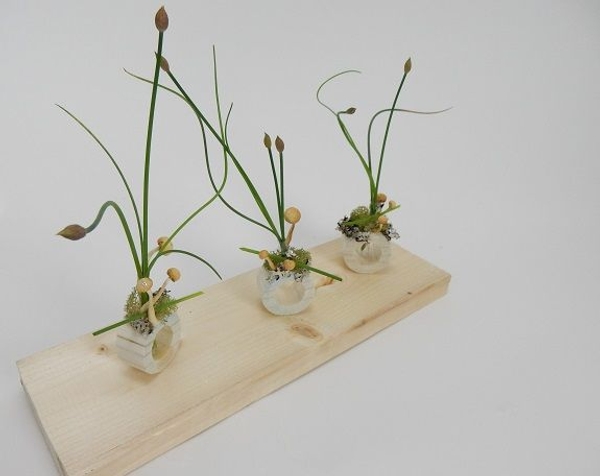 Chive flower heads with moss lichen and mushrooms in a dowel stick container Chive flower heads with moss lichen and mushrooms in a dowel stick container