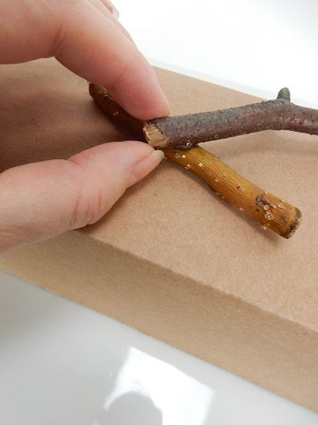 Place a small drop of hot glue on the twig and glue another twig to that Place a small drop of hot glue on the twig and glue another twig to that