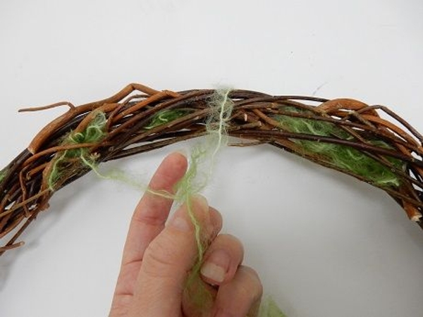 Create a loop in the wool by loosely wrapping the wool around the wreath Create a loop in the wool by loosely wrapping the wool around the wreath