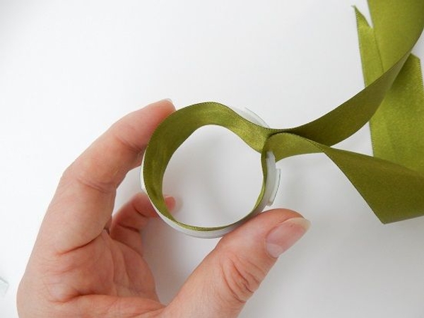 Open the ribbon and start to glue the middle point of the ribbon to the inside middle of the loop. Open the ribbon and start to glue the middle point of the ribbon to the inside middle of the loop.