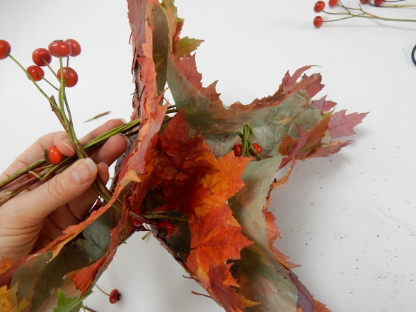 Cross the garland ends over and weave it back around and through the holes in the disk Cross the garland ends over and weave it back around and through the holes in the disk