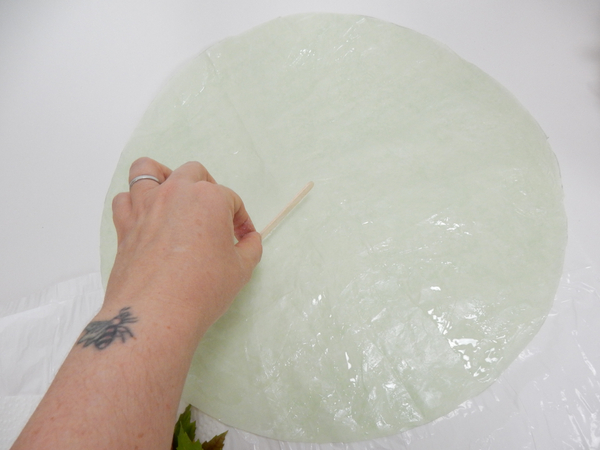 Spread a thin and even layer of floral glue on a round piece of tissue paper