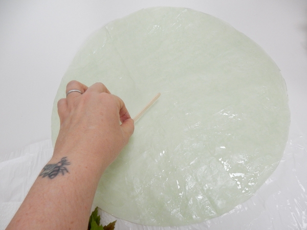 Spread a thin and even layer of floral glue on a round piece of tissue paper