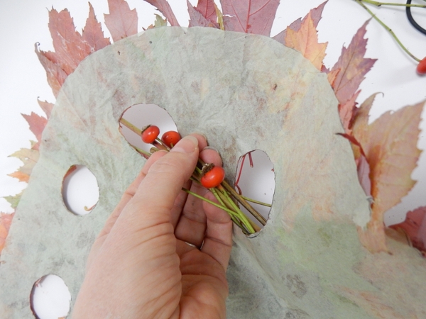 Weave the rosehip garland through the holes in the leaf disk Weave the rosehip garland through the holes in the leaf disk