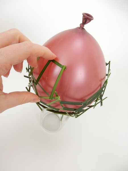Flip the balloon over to rest the grass side on the drinking glass Flip the balloon over to rest the grass side on the drinking glass