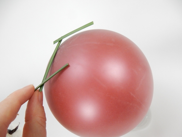 Place three grass snippets on the balloon and secure the end pieces with a small drop of flower glue. Place three grass snippets on the balloon and secure the end pieces with a small drop of flower glue.