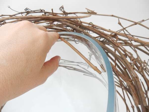 Hook one of the wreath twigs over the rim of the container to secure Hook one of the wreath twigs over the rim of the container to secure