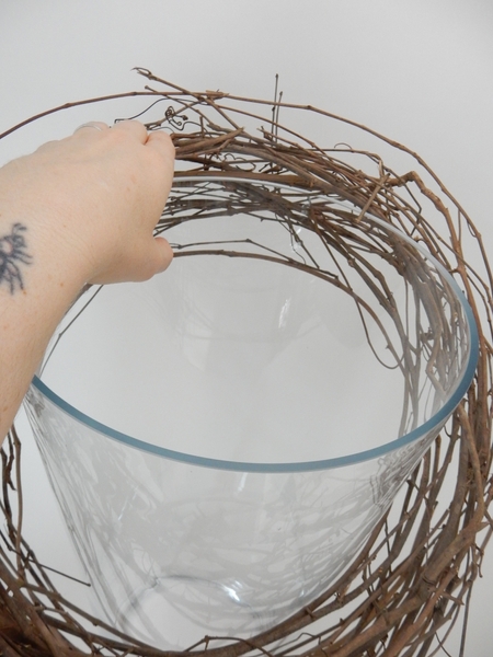 Hook the wreath over the rim of a glass container Hook the wreath over the rim of a glass container