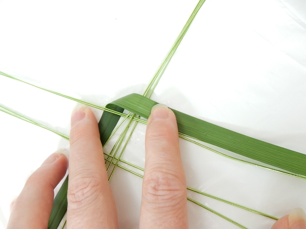 Bend the long side of the garland down to start the weave Bend the long side of the garland down to start the weave