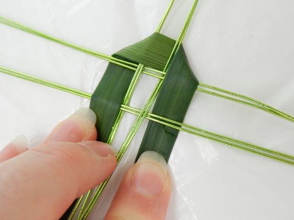 Weave the garland over the first two and under the next two strands Weave the garland over the first two and under the next two strands