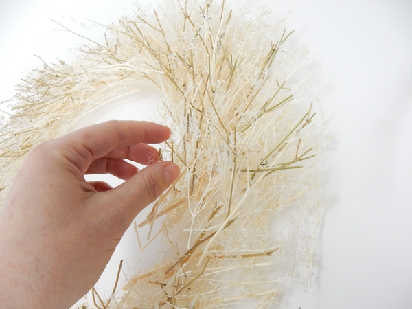 Place the wreath on a flat working surface and glue in a few green twigs