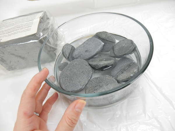 Carve pebbles out of floral foam and soak in water until the foam sinks  to the bottom of the container