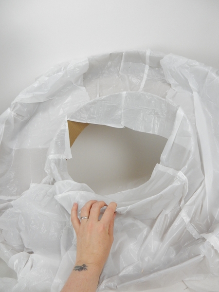 Line the cardboard wreath shape with a thin layer of plastic Line the cardboard wreath shape with a thin layer of plastic