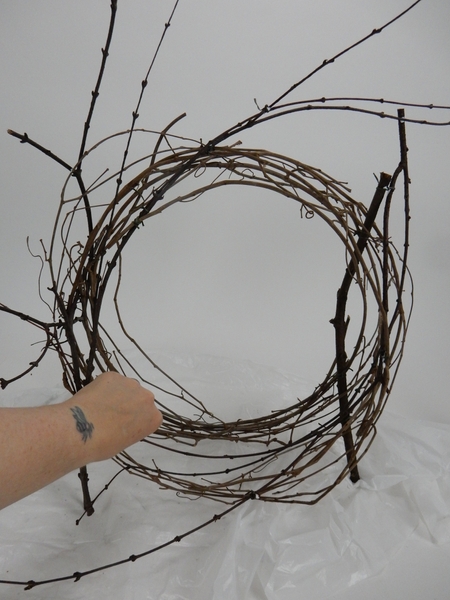 Snip away any stems that keep a vine wreath in place and loosen up the coils Snip away any stems that keep a vine wreath in place and loosen up the coils