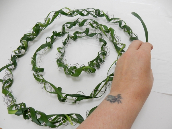 Continue to cover the wire by gently curving and coiling the grass around the spiral Continue to cover the wire by gently curving and coiling the grass around the spiral
