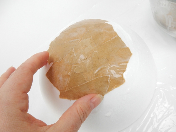 Overlap the brown paper to fully cover the white shape with brown paper. Overlap the brown paper to fully cover the white shape with brown paper.
