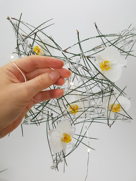 Add the fresh flowers and wrap the design with a string of tiny LED lights Add the fresh flowers and wrap the design with a string of tiny LED lights