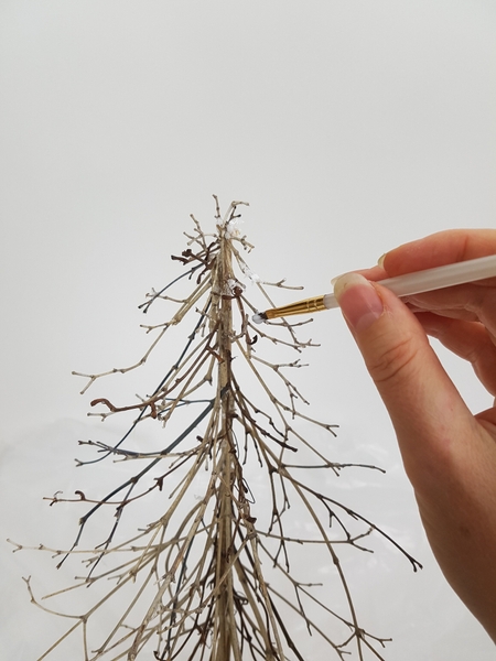 Paint the delicate branches with wood glue and sprinkle with fake snow Paint the delicate branches with wood glue and sprinkle with fake snow