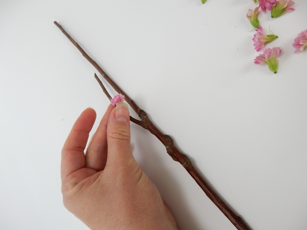 Decide on your design and glue the flowers to the wand with floral glue. Decide on your design and glue the flowers to the wand with floral glue.