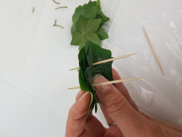 Pierce the second skewer through the leaves. Pierce the second skewer through the leaves.