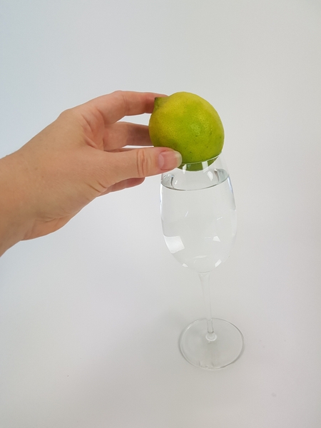 Place a lemon on the glass.  Any fruit or even vegetable or guard will work, as long as it is heavy for it's size and sits firm.