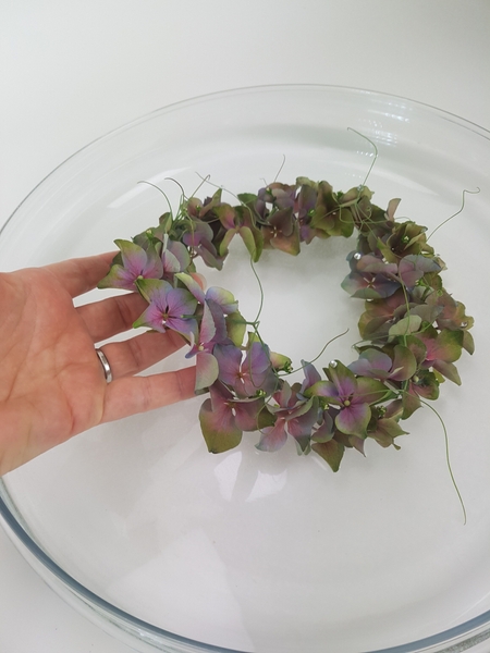 Set the hydrangea wreath on the water to float in the shallow container. Set the hydrangea wreath on the water to float in the shallow container.